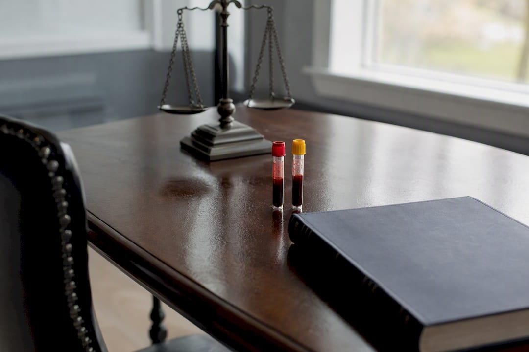 Granite Criminal Defense Law Office Desk With Blood Sample Vials And Scales Of Justice